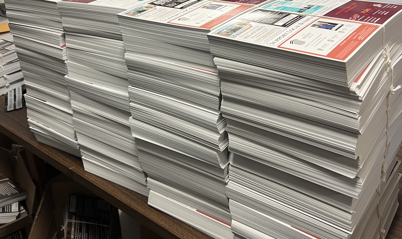 Stacks of printed 9x12 postcards bundled for USPS delivery